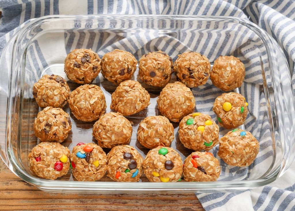 A top down shot of peanut butter oatmeal balls with mini m&ms in a clear glass baking dish