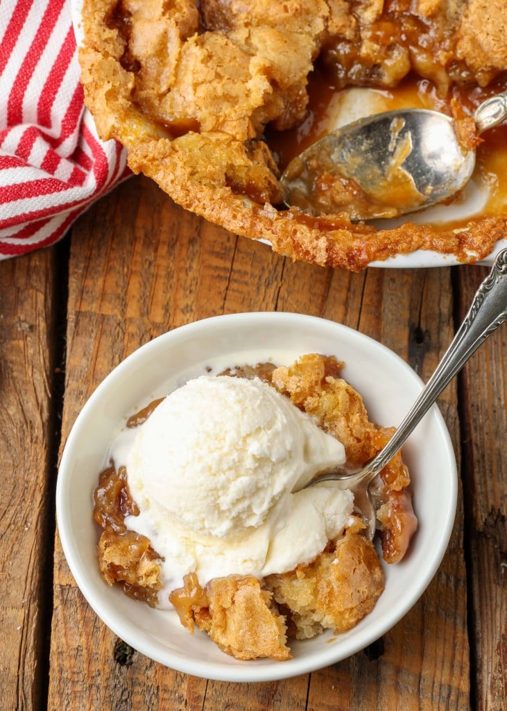 scoop ice cream over a dish of cobbler with pecans on wooden table 