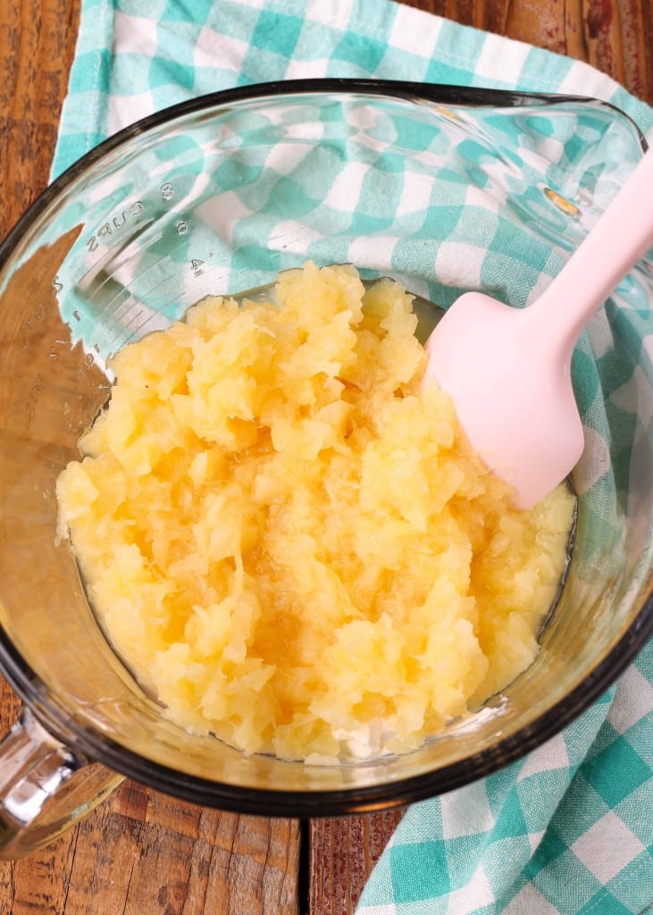 Crushed pineapple has been added to a clear glass mixing bowl.