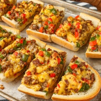 Sliced French bread with sausage, bell peppers, cheese, eggs, and onions