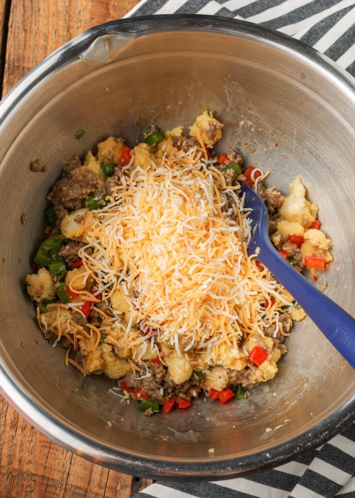 Bread, sausage, bell peppers, onions, and shredded cheese in silver bowl