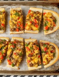 Sliced French bread with sausage, bell peppers, cheese, eggs, and onions