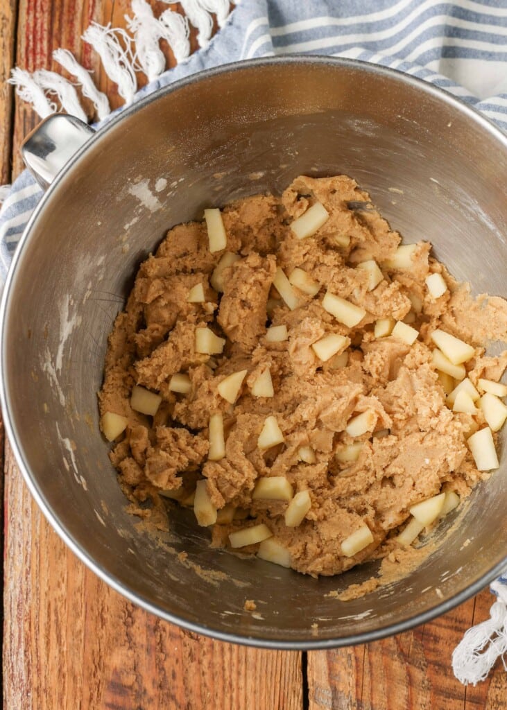 The dough for the cookies has been mixed in a large metal mixing bowl.