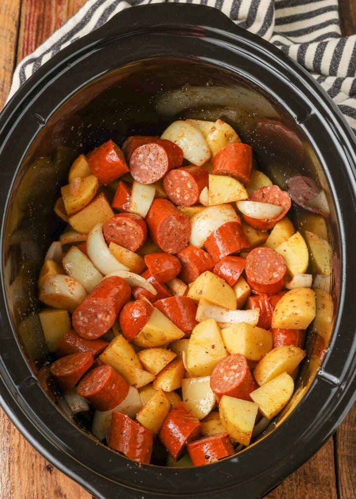 Raw sliced potatoes and kielbasa in slow cooker