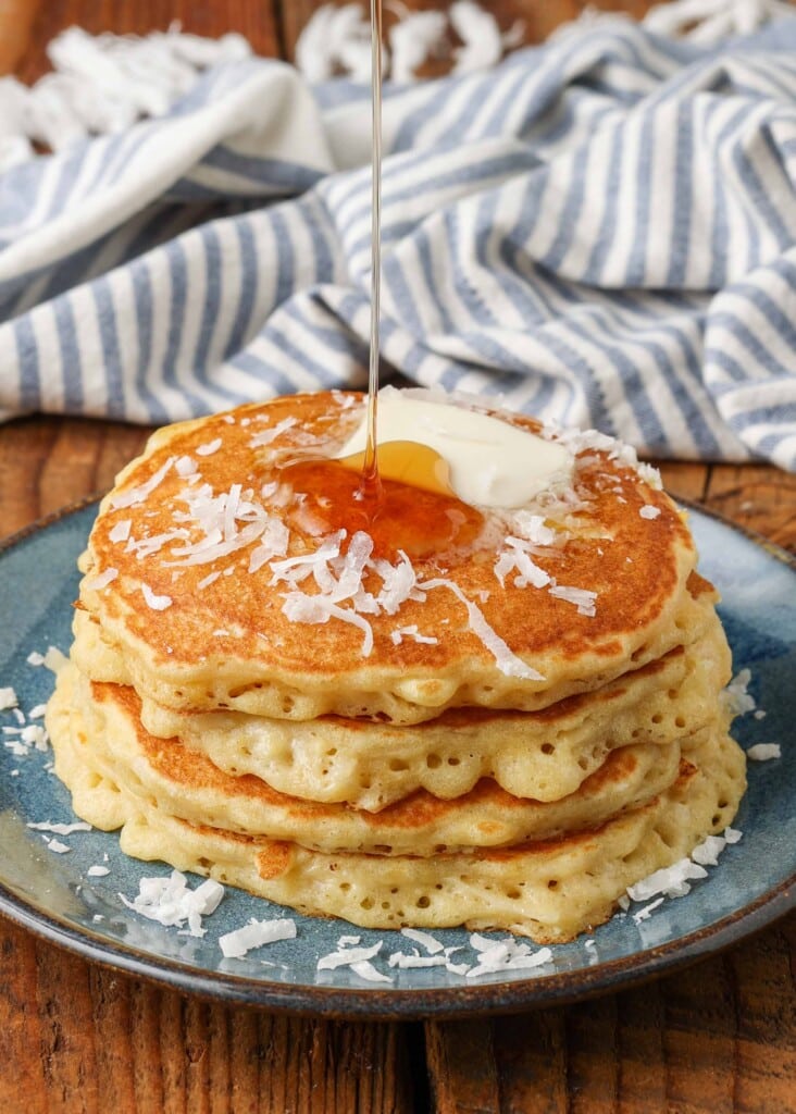 syrup drizzled over stack of pancakes on blue plate