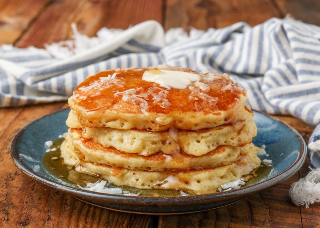 pancakes with butter and syrup on blue plate with sprinkling of coconut