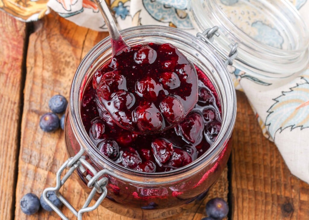 close up of Blueberry Compote in jar with silver ladle