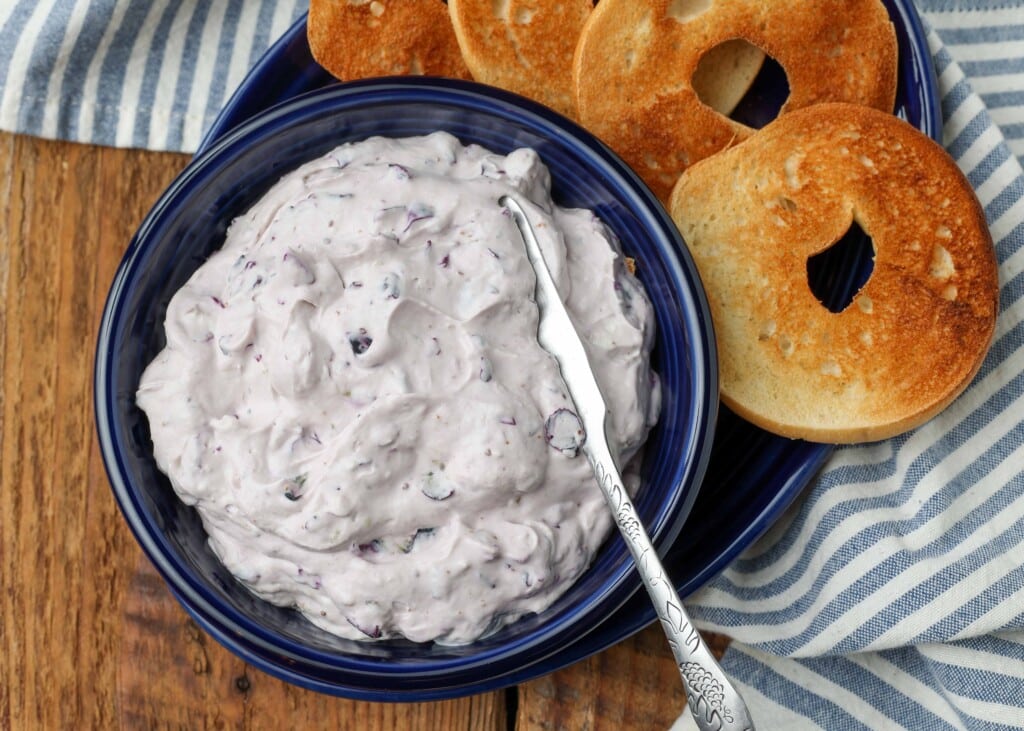 navy blue bowl holding cream cheese next to bagels