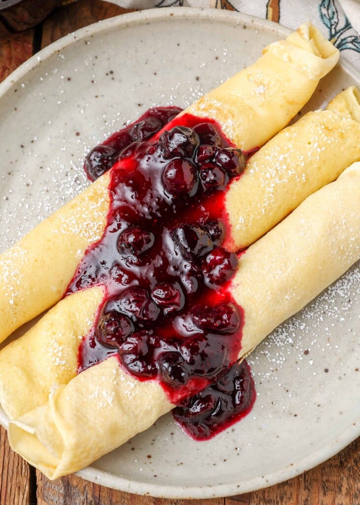 Close-up on crepes topped with compote and powdered sugar