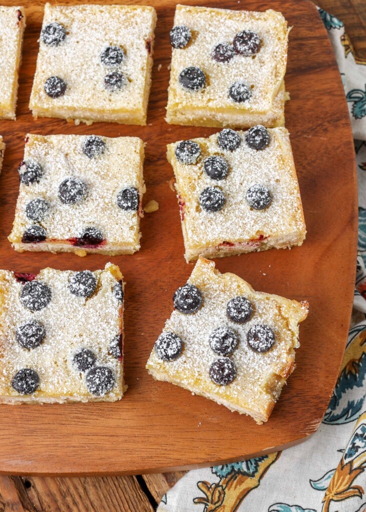 lemon bars with blueberries on cutting board