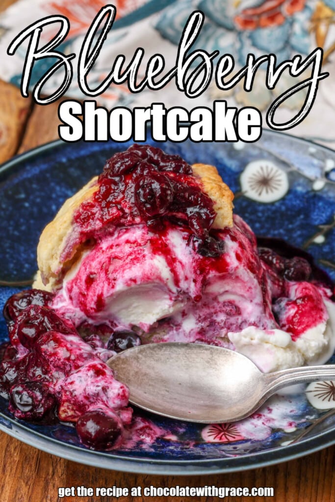 white lettering has been overlaid this close up shot of a metal spoon and blueberry shortcake on a blue plate. it reads, "blueberry shortcake"