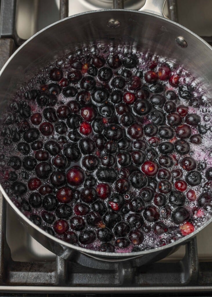 bringing the blueberry mixture to a boil on the stove in a metal pot