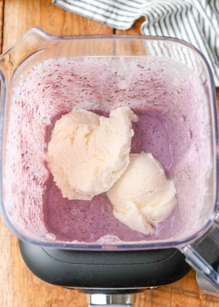 berries and milk in blender with scoops of ice cream on top
