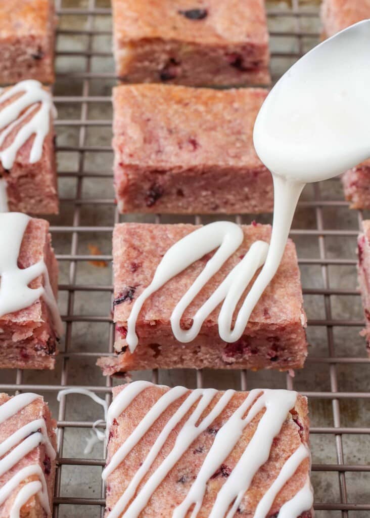 cherry bars on cooling rack with glaze drizzling over them