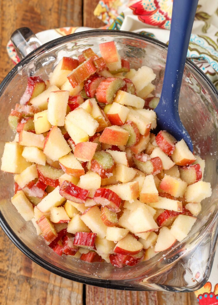 fruits tossed in sugar in bowl with blue spoon