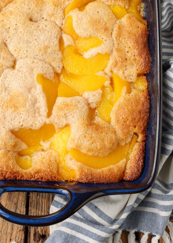 baked cobbler with peaches in blue baking dish with striped towel