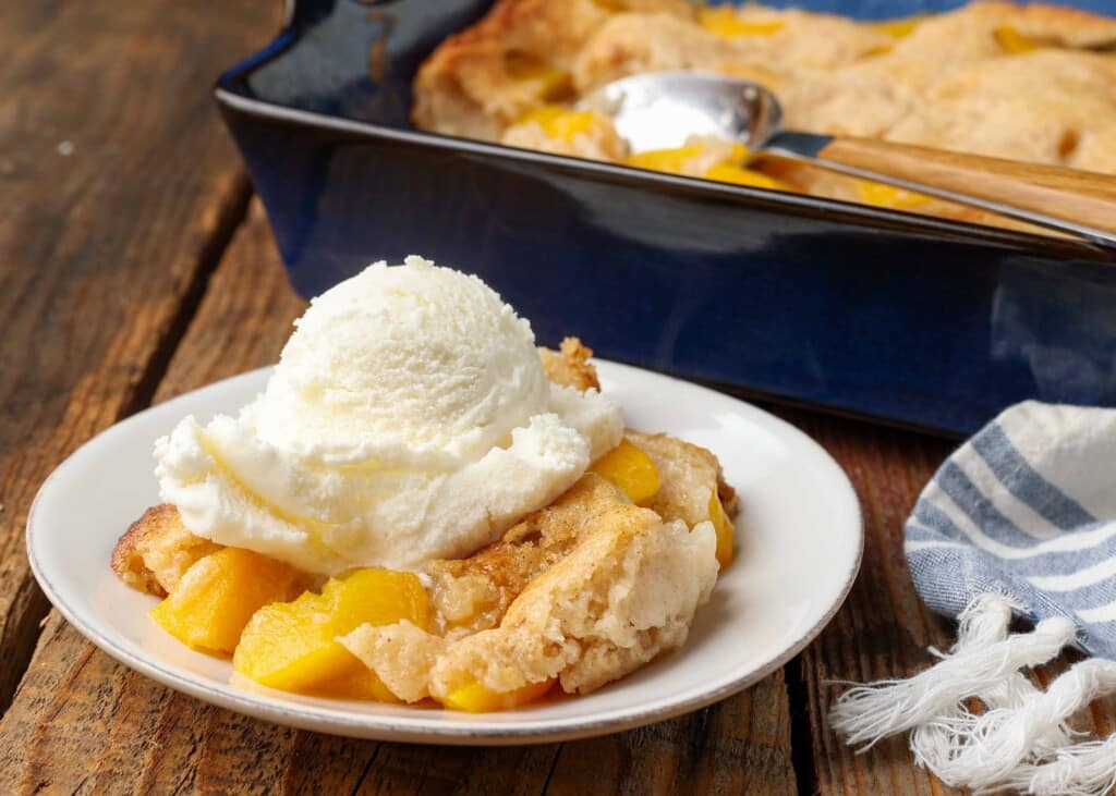 horizontal photo of cobbler with ice cream on white plate