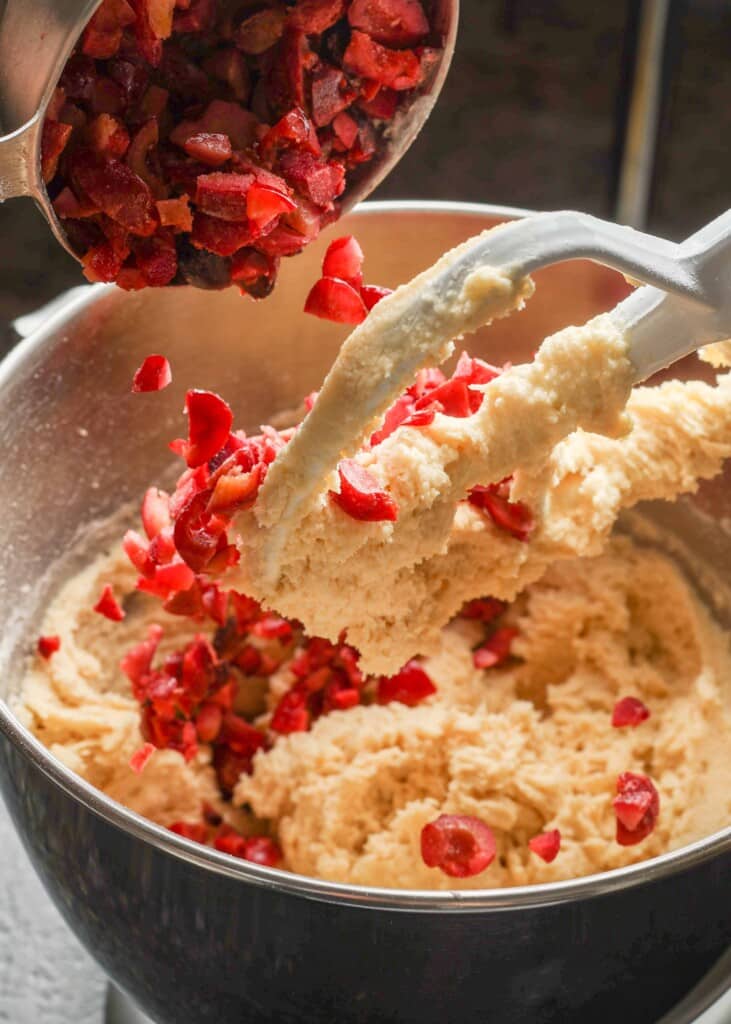 adding chopped cherries to cookie dough in a stand mixer