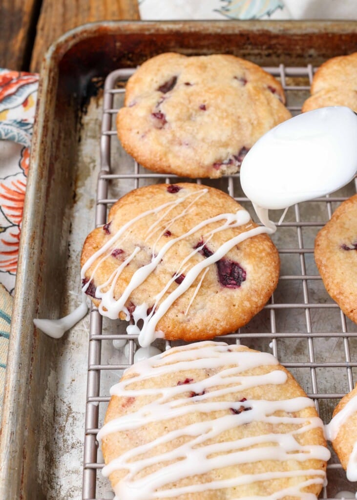 Soft cherry cookies on a rack over a pan with glaze drizzled over the top