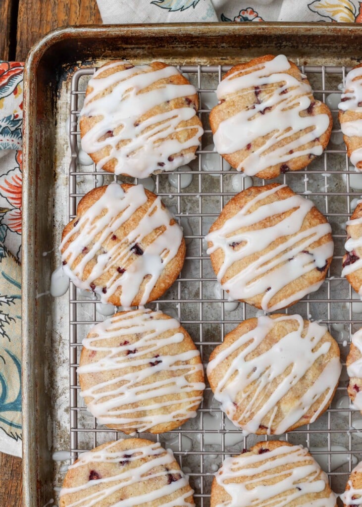 Soft cherry cookies on a rack over a pan with glaze drizzled over the top