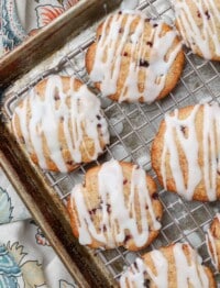 Soft cherry cookies on a rack over a pan with glaze drizzled over the top