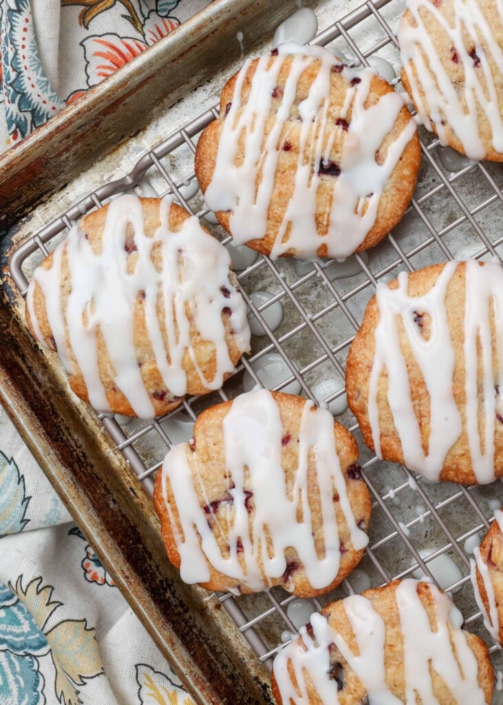 Soft cherry cookies on a rack over a pan with glaze drizzled over the top