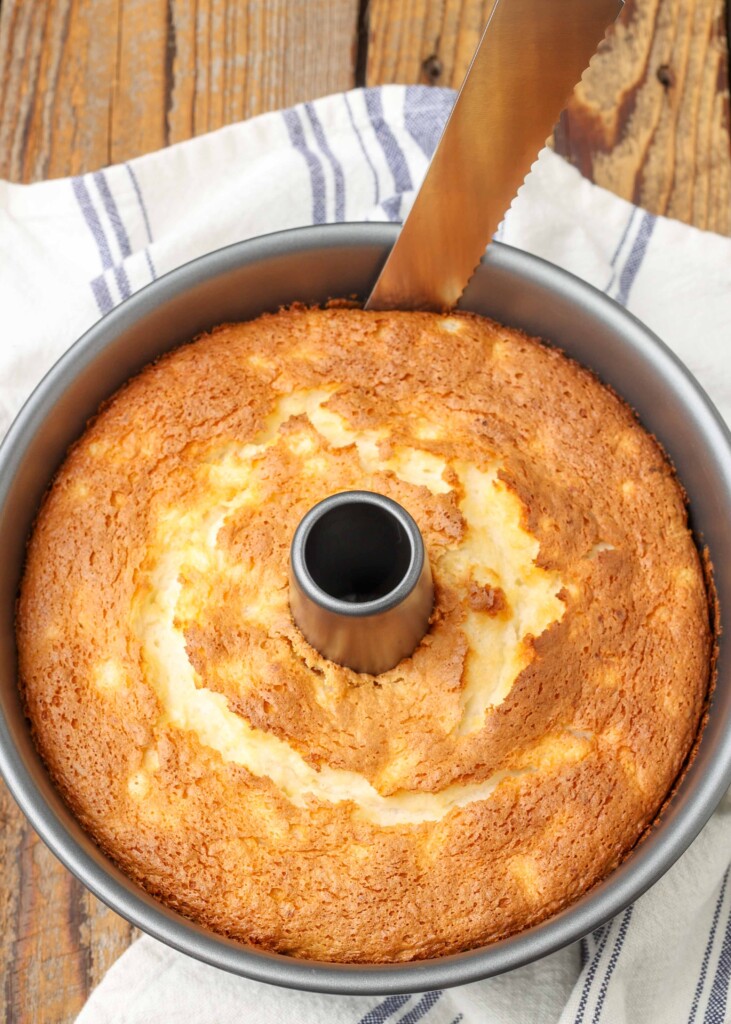 pineapple angel food cake in a tube pan with a knife running around the edge