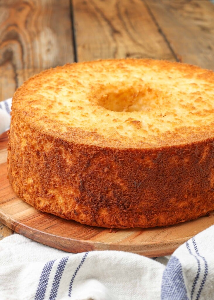 unsliced pineapple angel food cake on a wooden cutting board