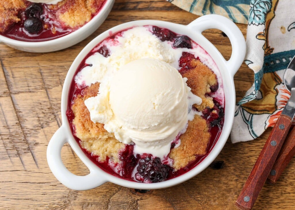 berry cobbler topped with melting vanilla ice cream