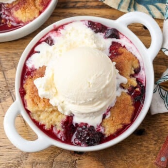 berry cobbler topped with melting vanilla ice cream