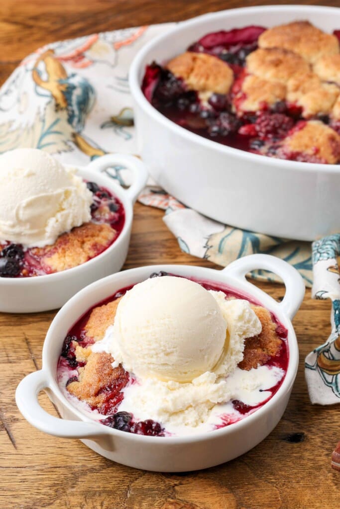 melting vanilla ice cream over berry cobbler