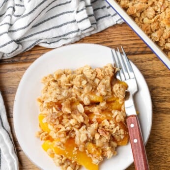 overhead shot of peach crisp on plate next to baking dish