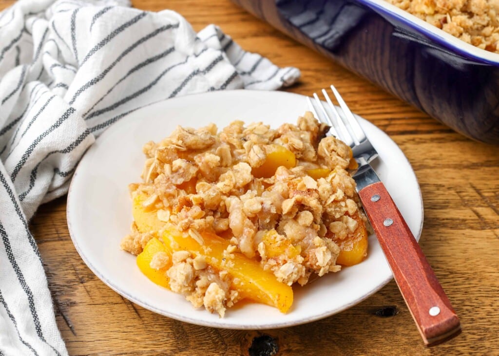 horizontal photos of peach crisp on plate with wooden fork