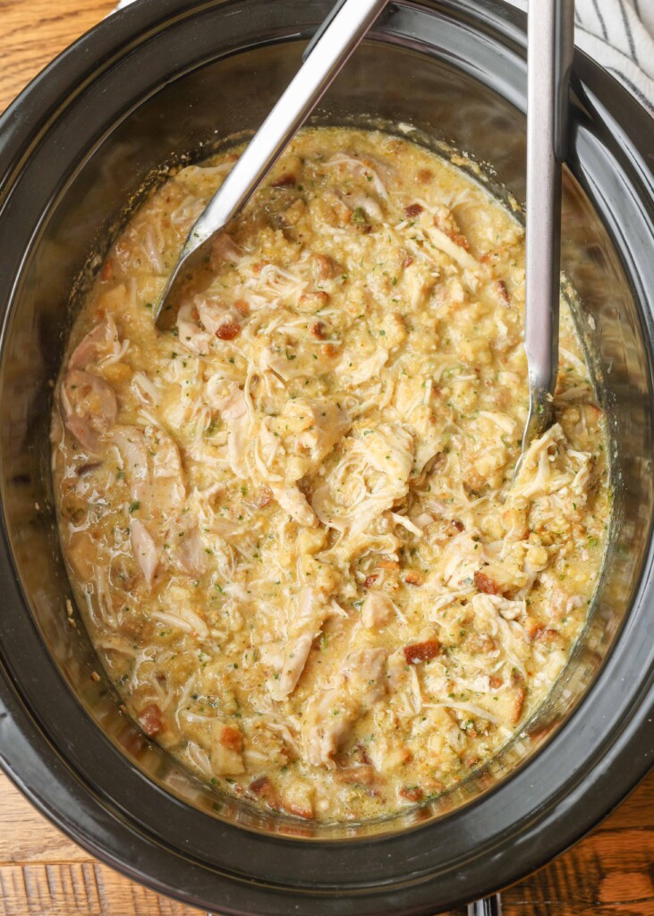 shredded chicken mixture in crockpot with tongs