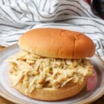 pulled chicken sandwich on plate next to crockpot