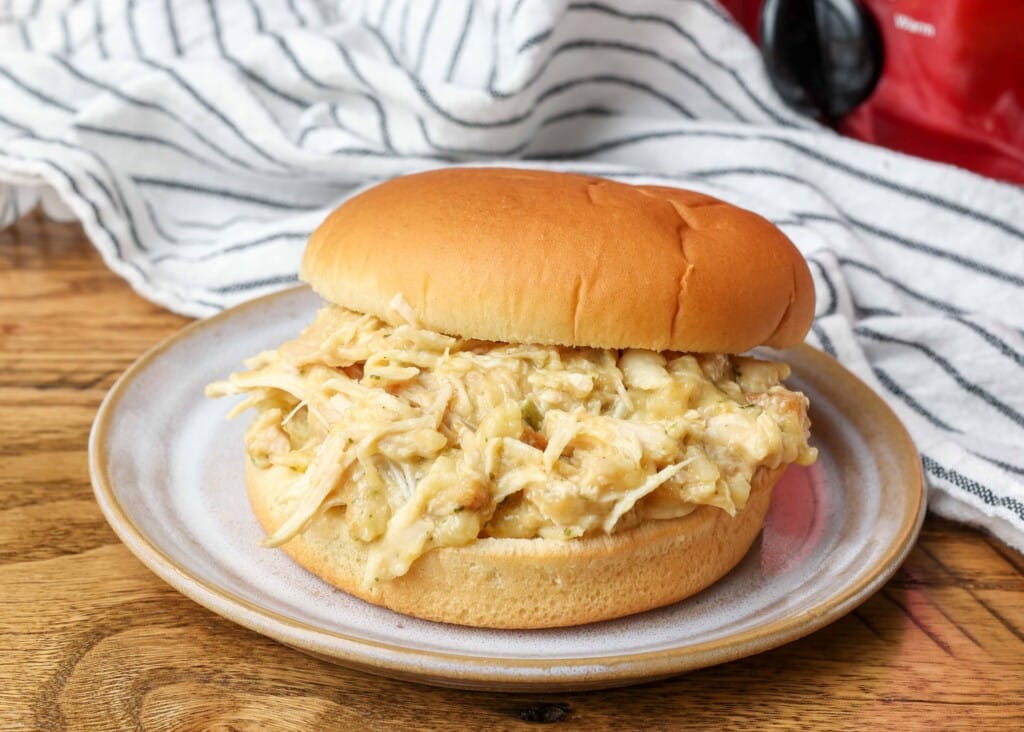 chicken sandwich on plate next to crockpot