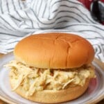 chicken sandwich on plate next to crockpot