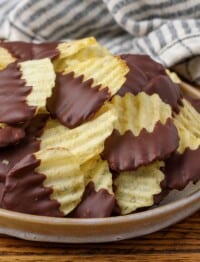 chocolate dipped potato chips on a plate with a striped towel in the background