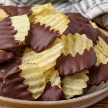 chocolate dipped potato chips on a plate with a striped towel in the background