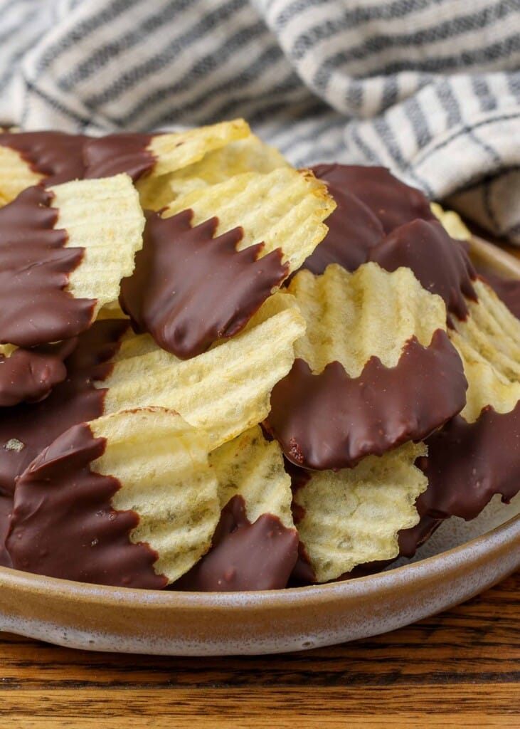 chocolate dipped potato chips on a plate with a striped towel in the background