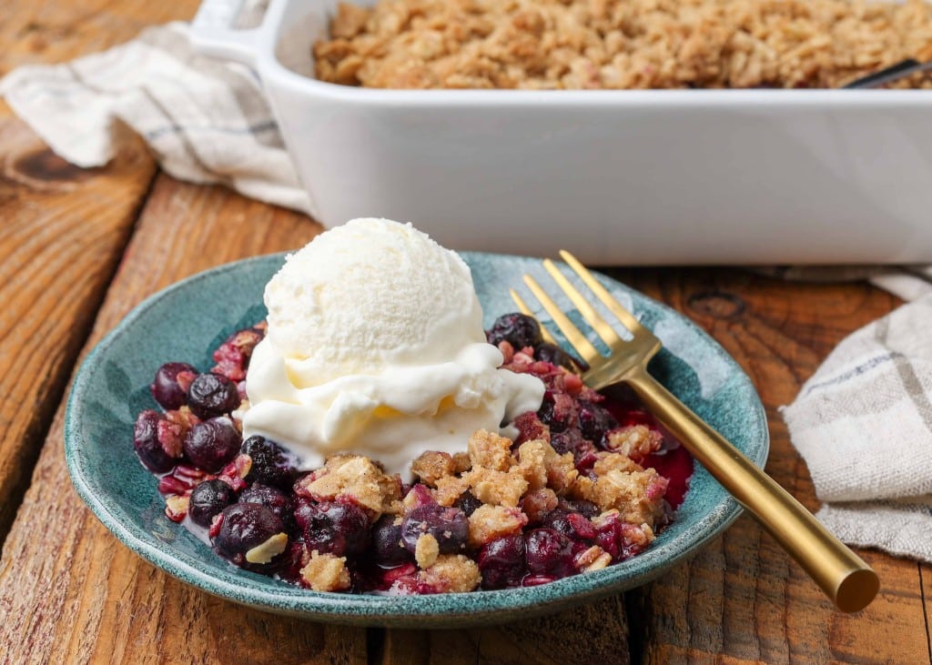 berry crisp on blue plate topped with scoop of ice cream