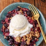 Blueberry Crisp with vanilla ice cream on blue plate with gold fork