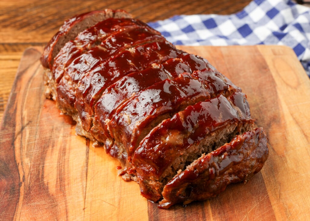 shiny glazed meatloaf sliced on cutting board
