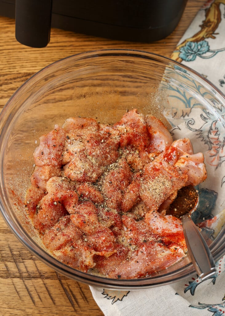 chicken in mixing bowl with spices