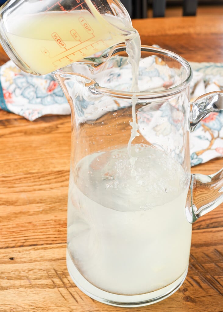 lemonade being mixed in a glass pitcher