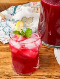 blueberry lemonade in a glass garnished with lemon and mint