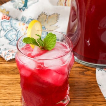 blueberry lemonade in a glass garnished with lemon and mint