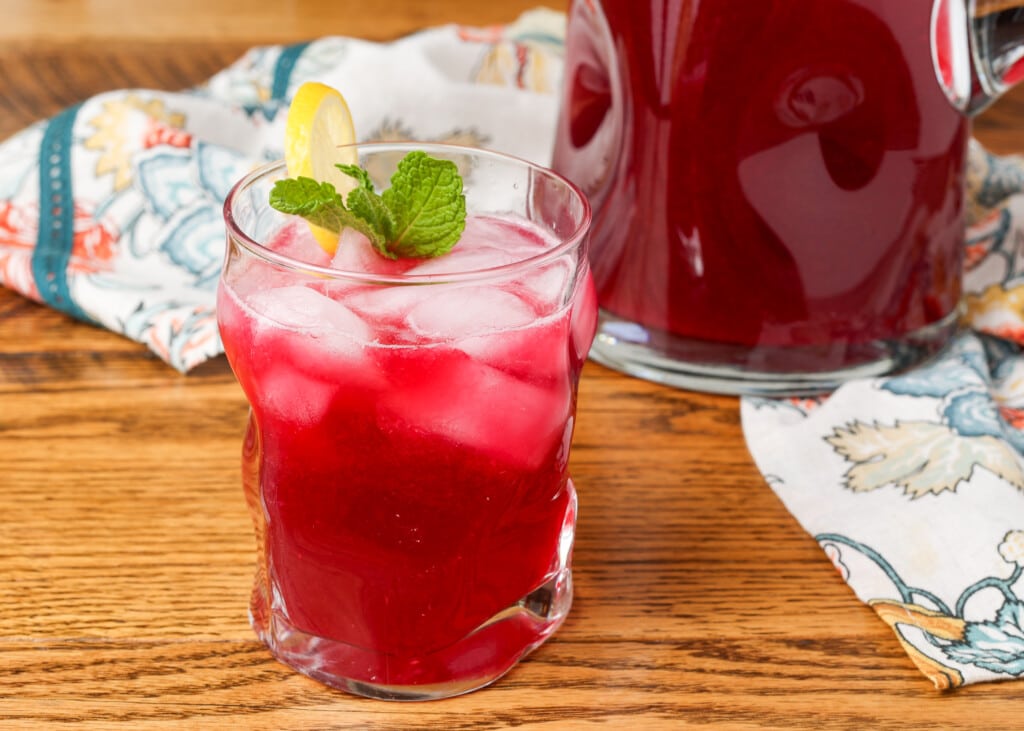 blueberry lemonade in a glass garnished with lemon and mint 