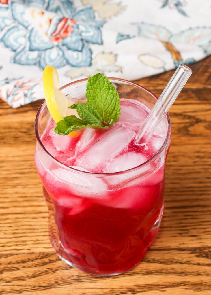 blueberry lemonade in a glass garnished with lemon and mint
