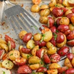 rosemary garlic roasted potatoes on a sheet pan with a spatula